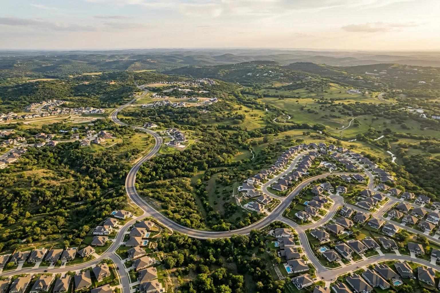 Aerial view of Texas Hill Country west of Austin showing suburban homes among rolling green hills