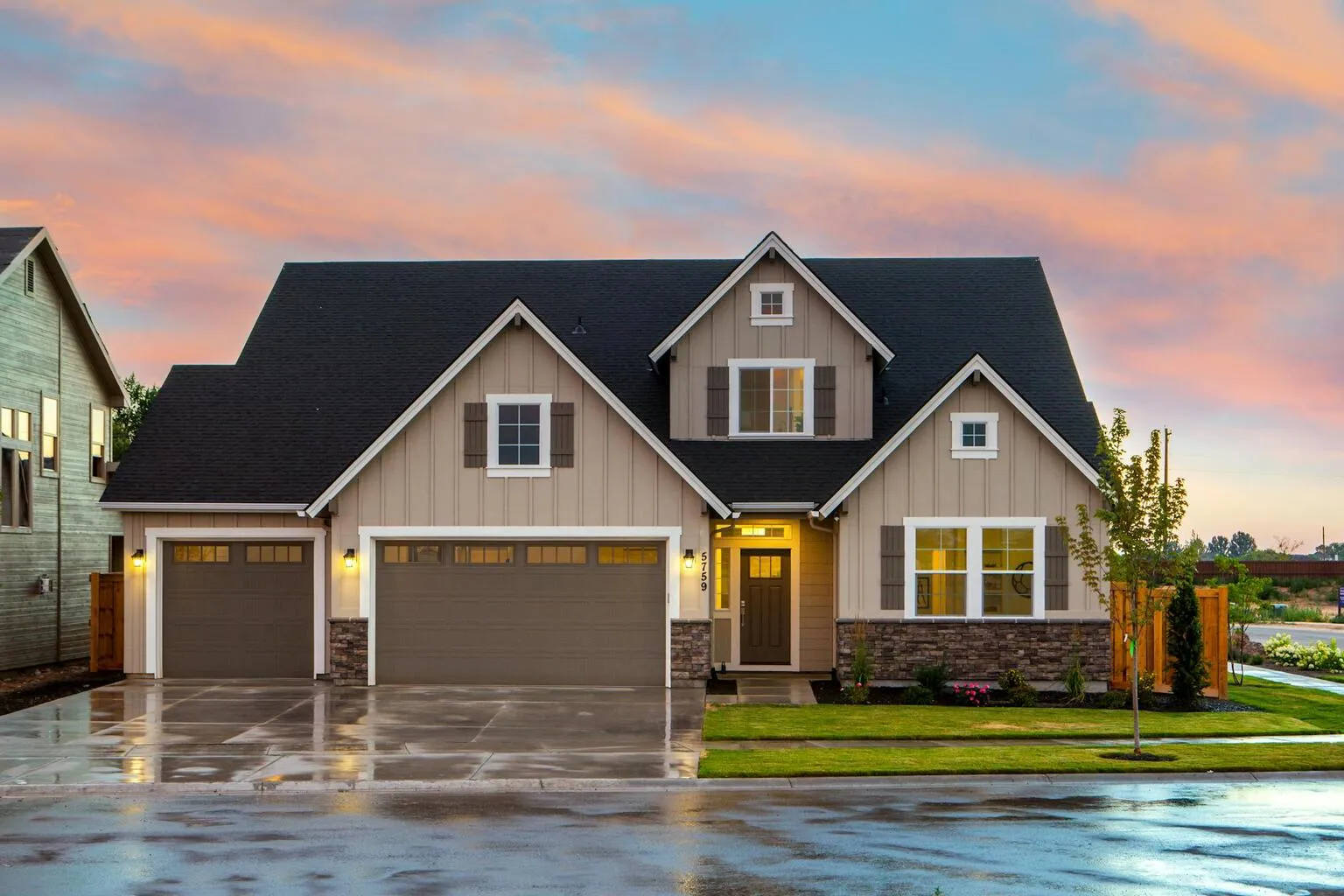 Modern suburban home with two-car garage and landscaped yard at dusk