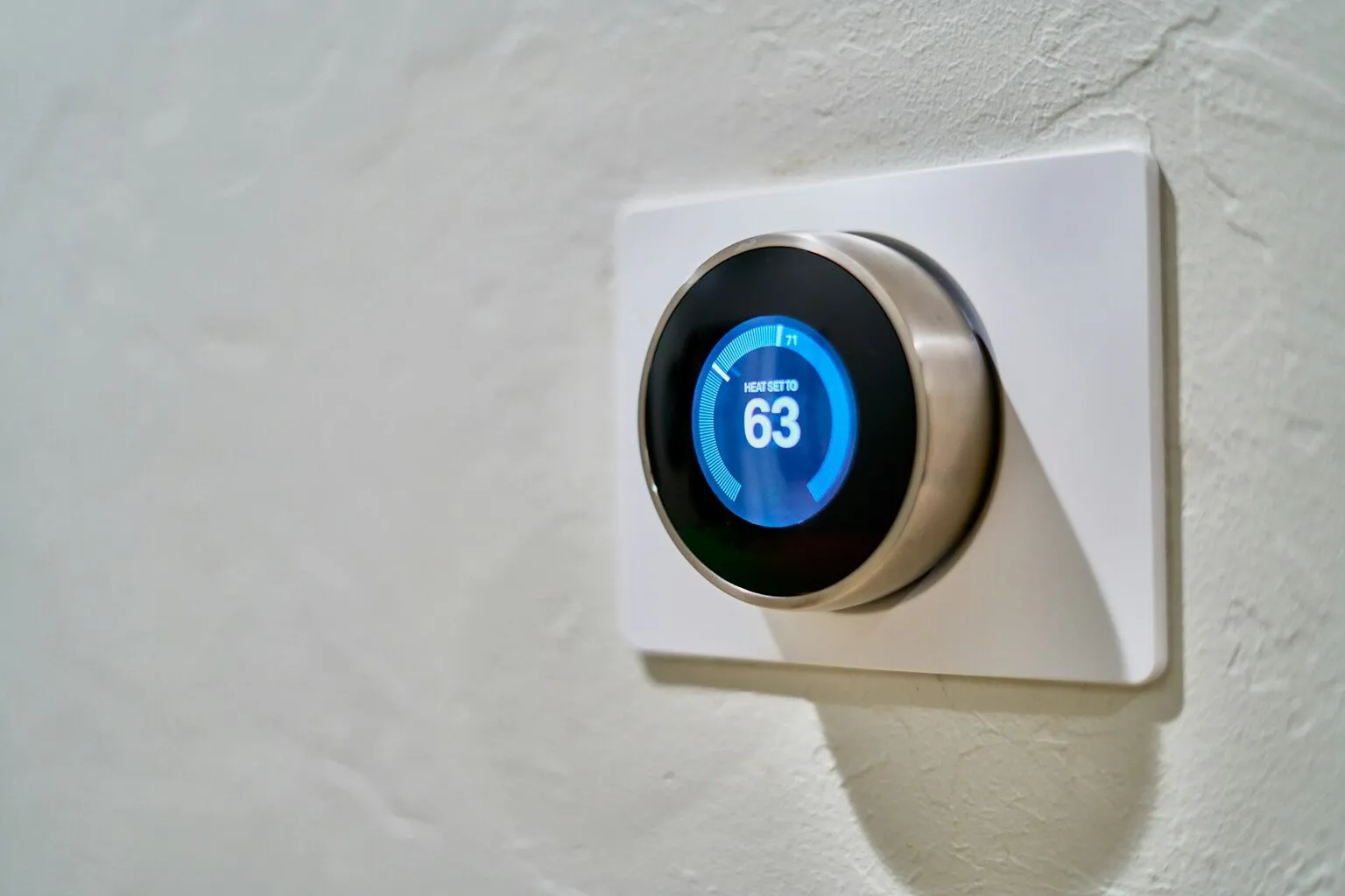 Nest smart thermostat displaying temperature on a modern home wall