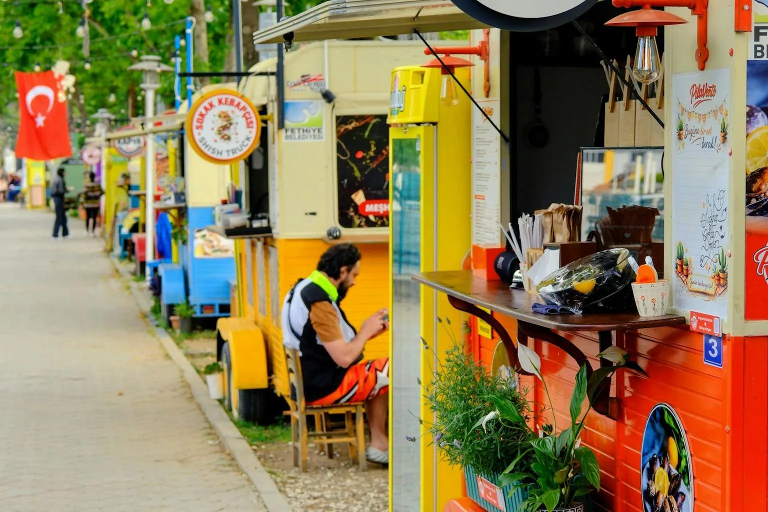 Food trucks parked in an outdoor food park with colorful signs and string lights