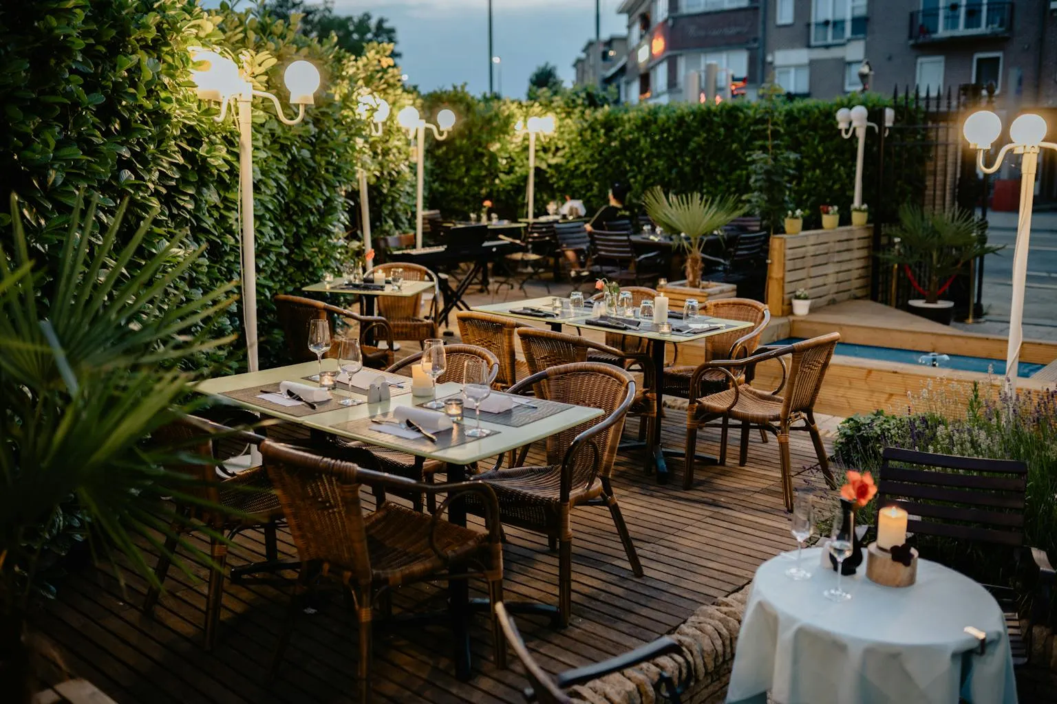 Outdoor restaurant patio with wicker chairs and warm ambient string lights for evening dining