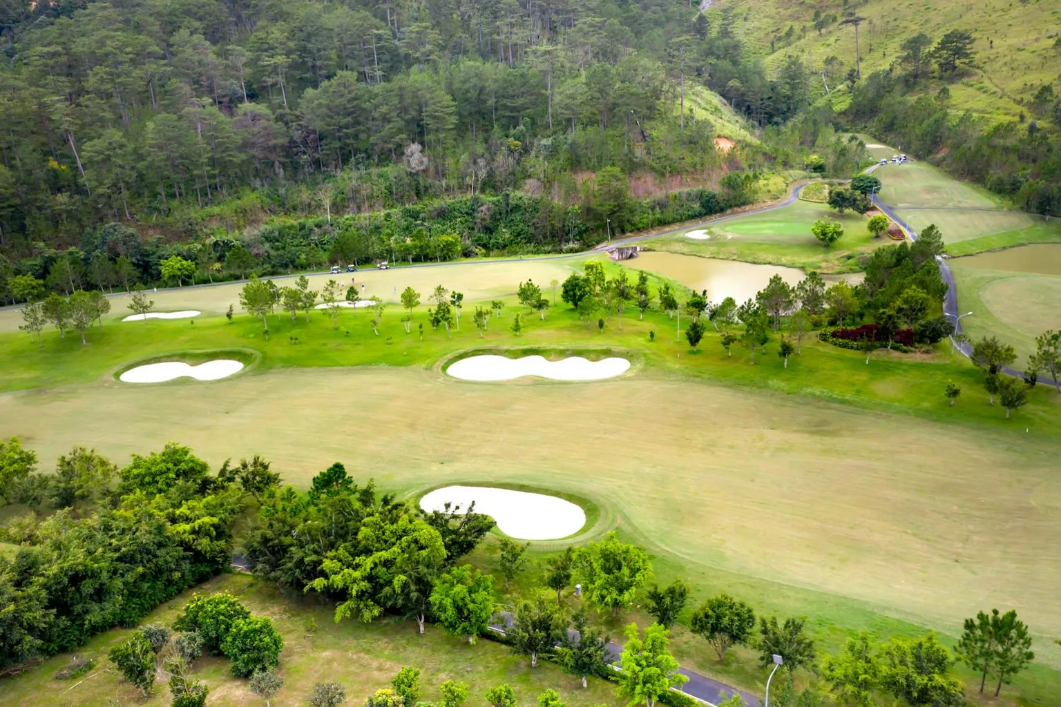 Overhead view of golf course featuring green fairways, sand traps, and surrounding landscape