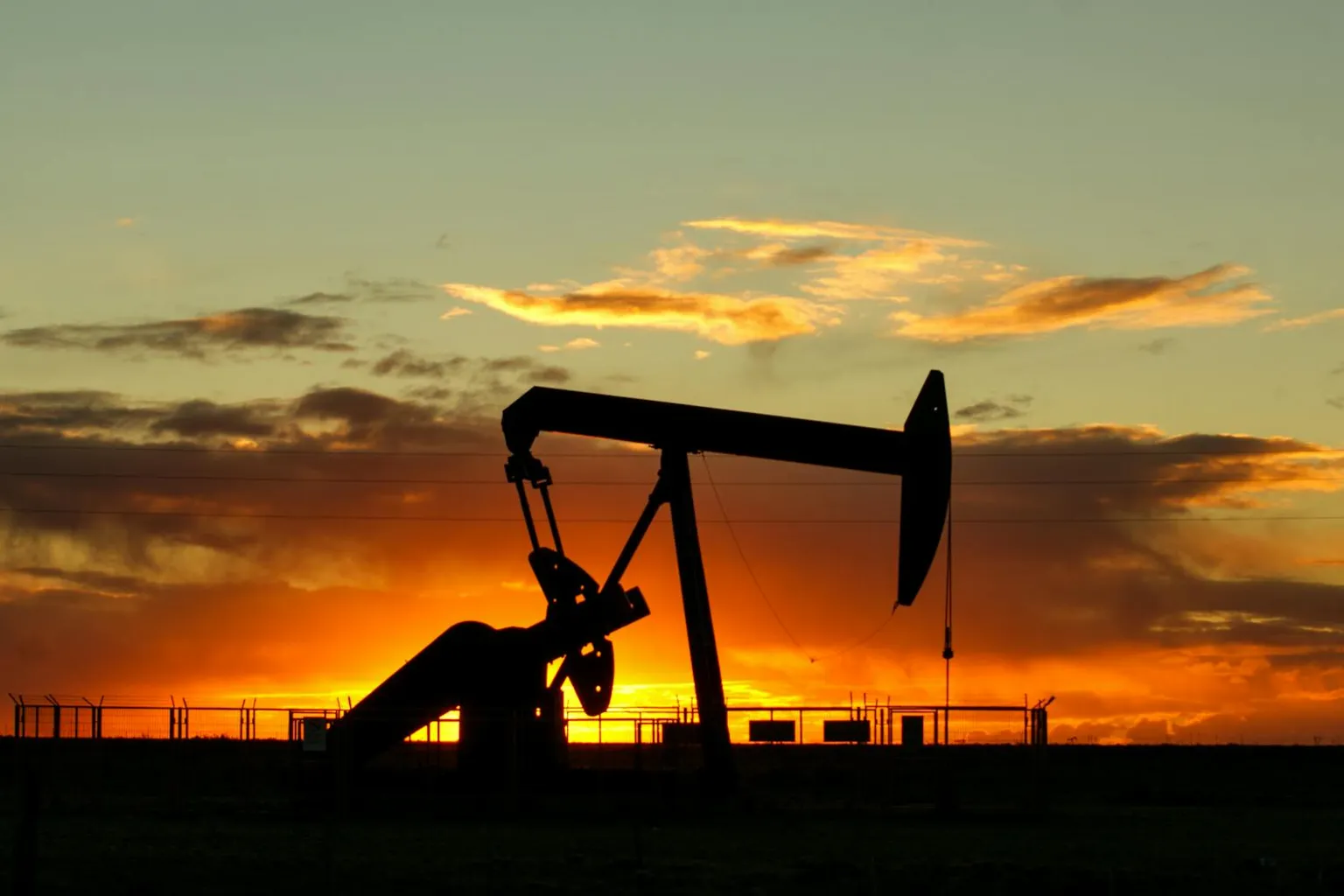 Oil pump jack operating on open rural Texas landscape at sunset