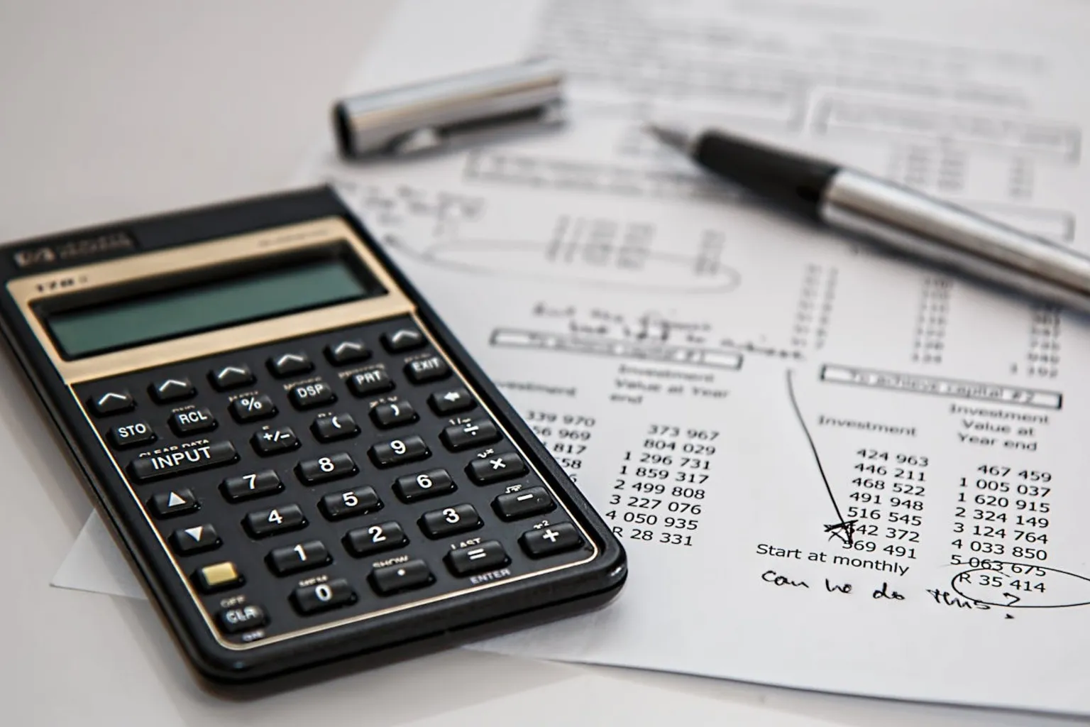 Black calculator and ballpoint pen on financial planning documents