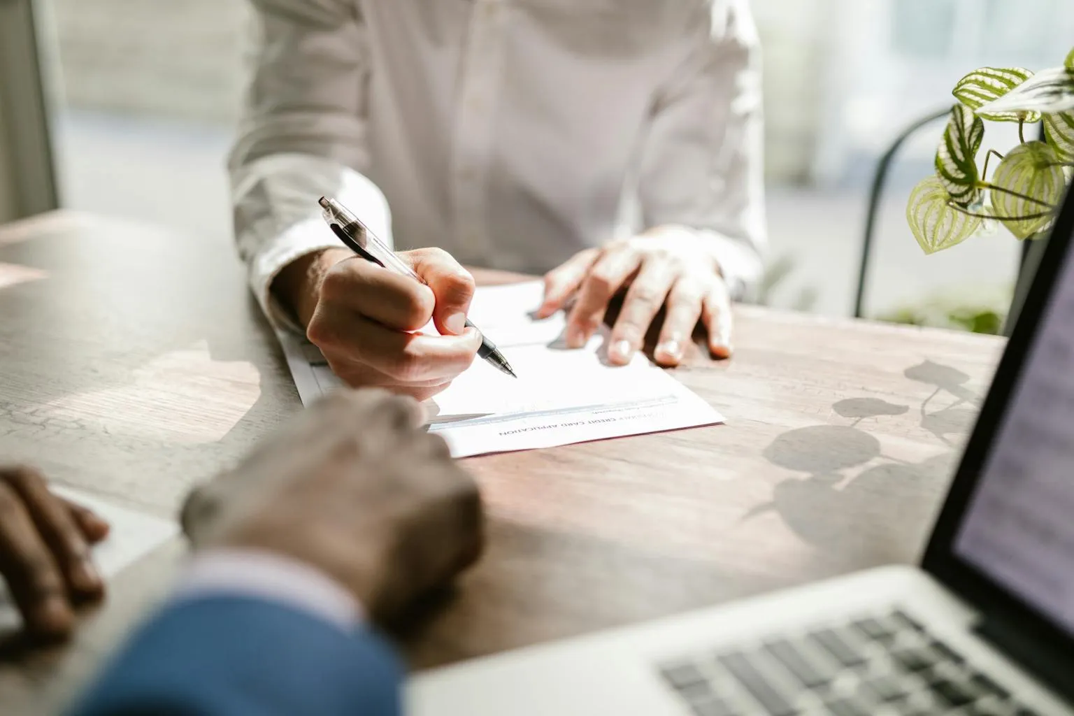 Person signing real estate closing documents at desk with pen
