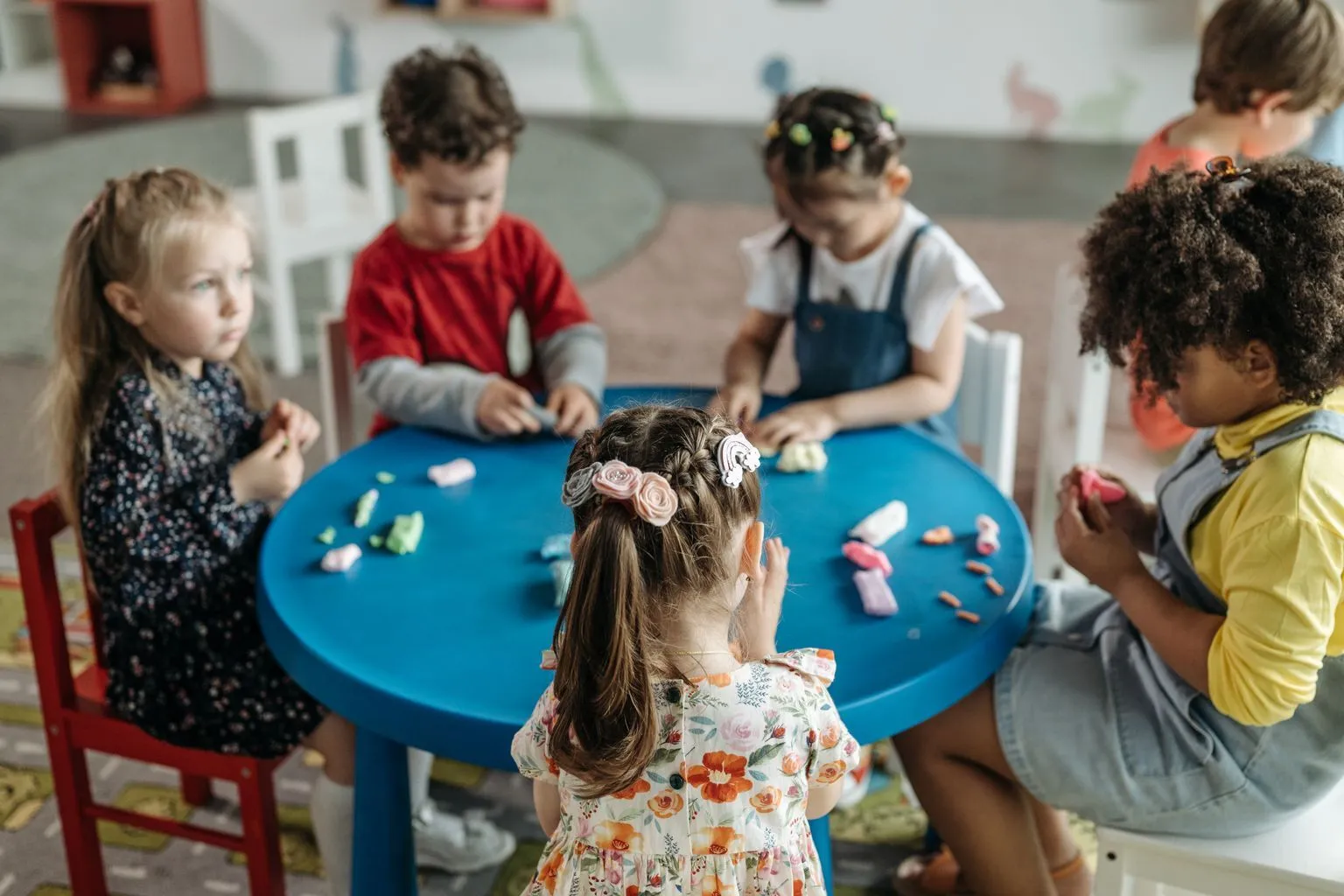 Children playing with clay and art materials in a colorful Austin preschool classroom