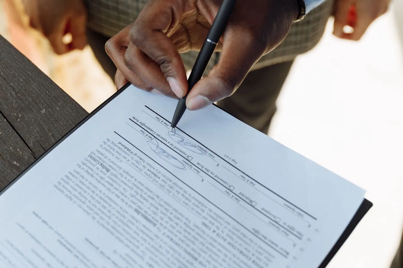 Two people signing a real estate financing contract on a clipboard with a pen