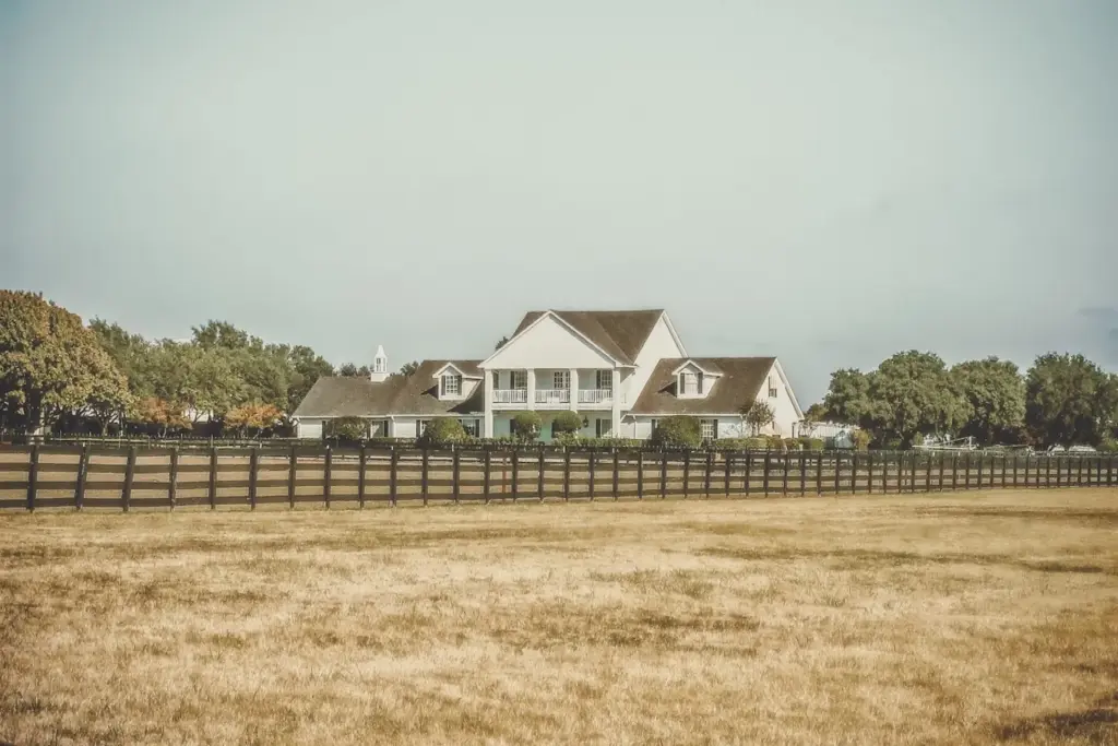 White two-story Texas ranch home behind a wood fence