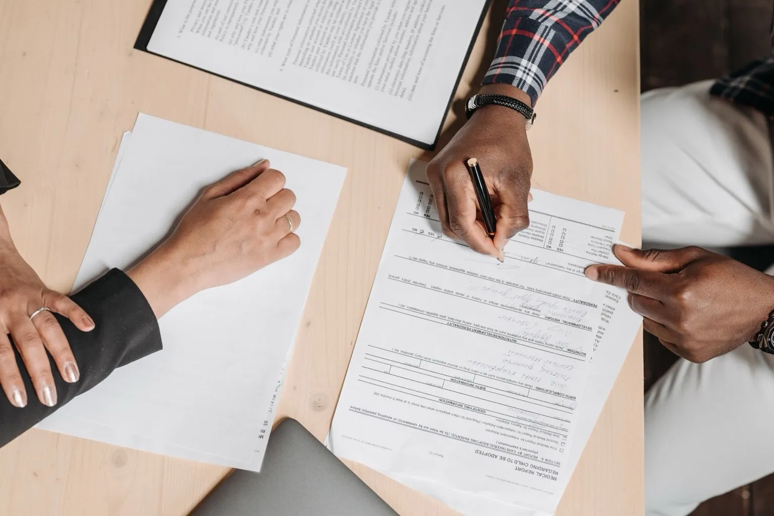 Buyers reviewing subdivision documents and deed restrictions with a real estate professional at a desk