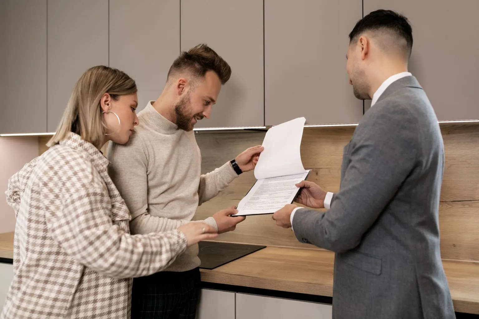 Home sellers reviewing pricing and contract documents at a kitchen counter