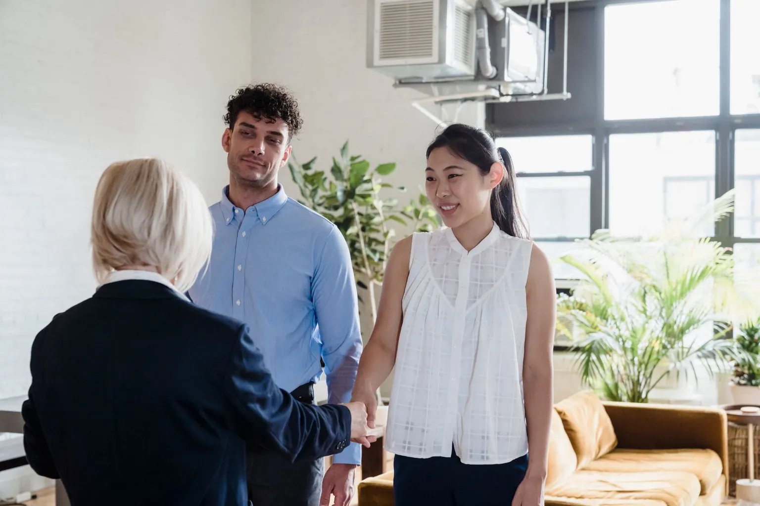 A real estate agent shaking hands with a couple in a home